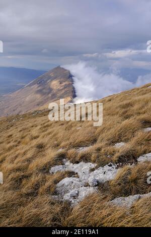Golden, dry grass and distant mountain ridge covered by thick mist and lighten by soft sunlight on Dry mountain (Suva planina), Serbia Stock Photo