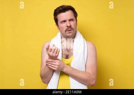 Health, medicine and lifestyle concept. Man measuring own pulse, raise one arm and touch vein on hand. Studio shot on yellow wall. Stock Photo