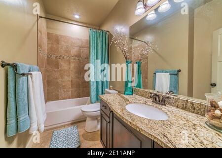 Bathroom interior with warm toned tiles rectangular bathtub toilet and vanity Stock Photo