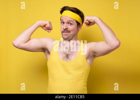 Young man showing arms muscles smiling being proud. Fitness concept. Stock Photo