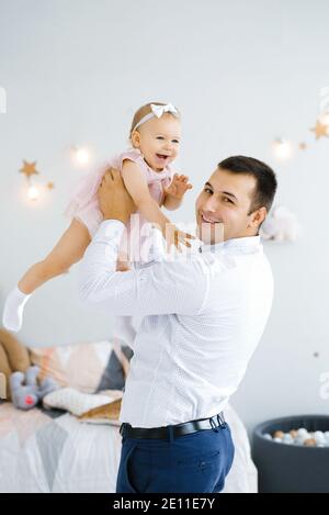 Father lifting baby girl. Happy father picks up and throws his lifting a small child. Home atmosphere, happy family laughing baby Stock Photo