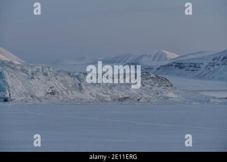 Dark winter season on Svalbard. Glacier Tunabreen with surrounding mountains in twilight  in February, Tempelfjorden, Spitsbergen, Svalbard, Norway Stock Photo