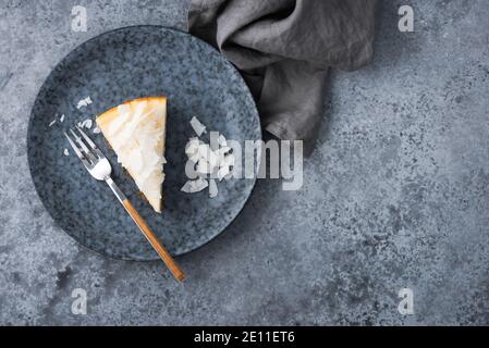 Slice of vegan coconut cheesecake on a blue plate, top view. Vegan plant based protein cheesecake Stock Photo