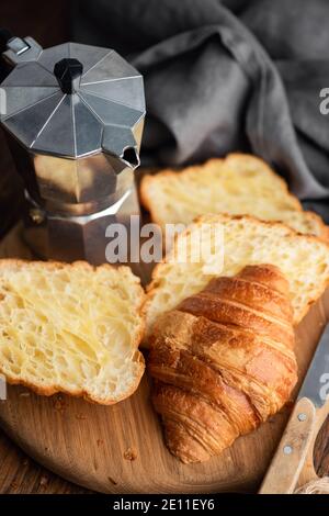 Croissants cut in halves and italian coffee maker, moka pot Stock Photo