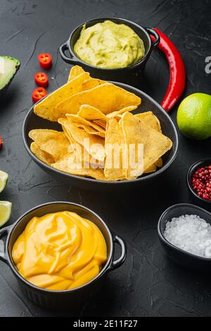 Nachos and guacamole and cheese sauces, on black background Stock Photo