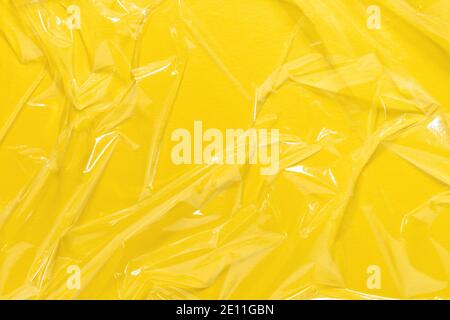 Wrinkled cling film, plastic texture, vinyl yellow art background. Stock Photo