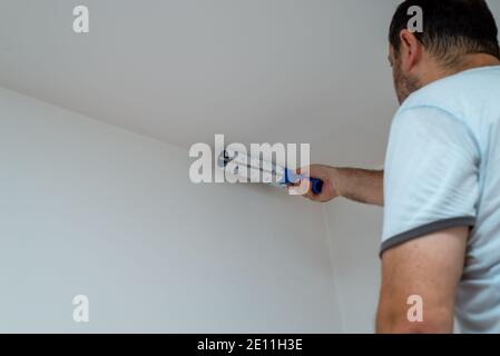 Man painting a ceiling in white color with a roller Stock Photo