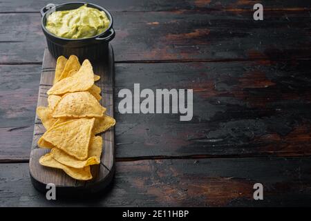 Mexican crispy snack, nachos chips and cheese guacamole avocado sauces, on old wooden table with copy space for text Stock Photo