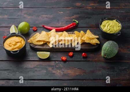 Mexican crispy snack, nachos chips and cheese guacamole avocado sauces, on old wooden table Stock Photo