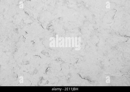 Close-up of an aged and cracked smooth natural marble stone wall or flooring. High resolution full frame textured background in black and white. Stock Photo
