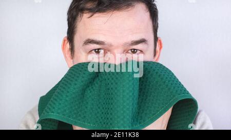 Close-up of a Caucasian man wiping his face with a green towel. Stock Photo