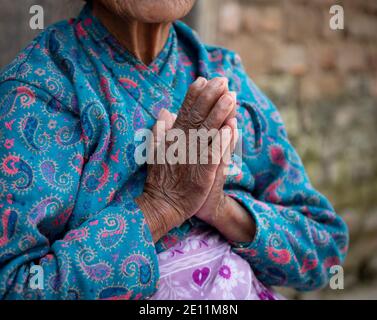 Unrecognized elder woman wearing blue cloths crossing her wrinkled hands. Aging age process Stock Photo