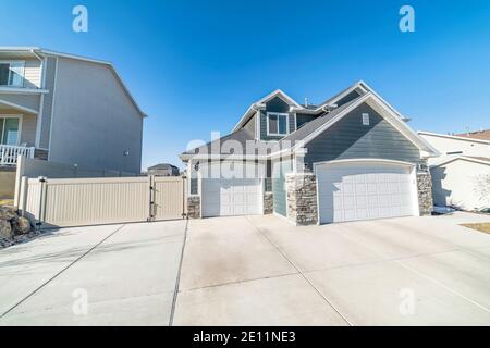 House with attached two car garage and gray wall siding against blue sky view Stock Photo