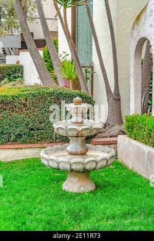 Three tiered stone fountain on the lawn of a beautiful home in Long Beach CA Stock Photo