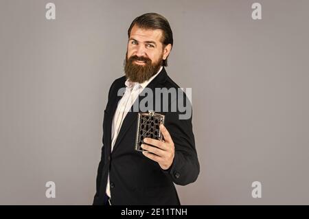 cheers. Hip flask for whiskey. vintage gentleman gift shop. Brutal businessman drinking alcohol. Man with his booze flask. man drinks strong alcohol from iron flask while relaxing. copy space. Stock Photo