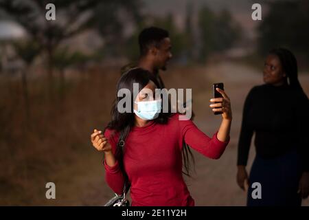 an african lady wearing a mask and taking a selfie Stock Photo