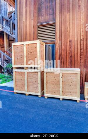Crate boxes stacked against wooden exterior wall of building with vent window Stock Photo