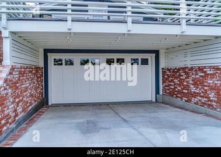 White garage door under spacious balcony with white railing in San Diego CA Stock Photo