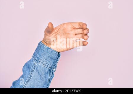 Hand of caucasian young man showing fingers over isolated pink background holding invisible object, empty hand doing clipping and grabbing gesture Stock Photo