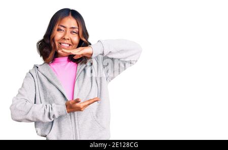 Young beautiful mixed race woman wearing casual sporty clothes gesturing with hands showing big and large size sign, measure symbol. smiling looking a Stock Photo