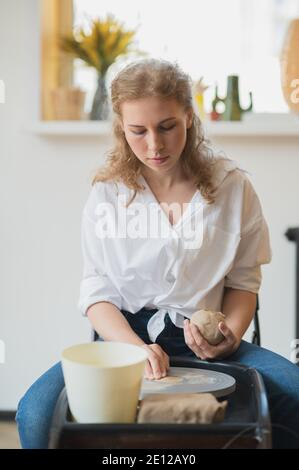 Close-up view of woman hands working on pottery wheel and making clay pot. Hands sculpts a cup from clay pot. Workshop on modeling on the potter's Stock Photo