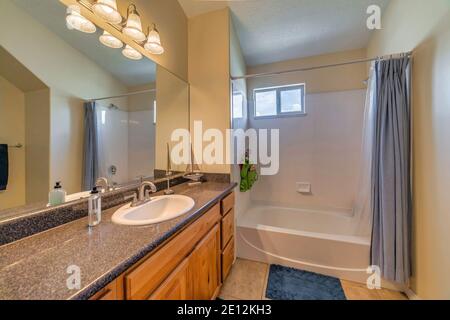 Sink on marble countertop over brown cabinets against mirror and bathroom lights Stock Photo