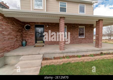 Front view of two storey house with spacious open porch and red brick wall Stock Photo