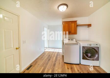 Laundry room with washing machine and dryer under cabinet mounted on white wall Stock Photo