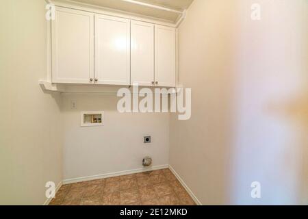 Laundry room with wall cabinet above an empty space for washing appliances Stock Photo