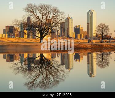 People relaxing at Trammell Crow Park with a view of the Dallas, Texas skyline in the background and reflecting pond in the foreground. Stock Photo
