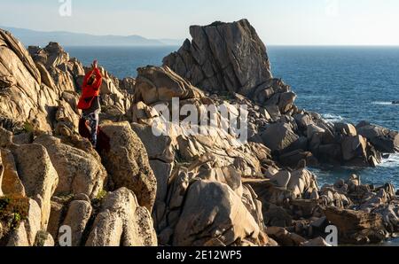 Sporty Woman Stands On The Granite Rock Coast, Santa Teresa Di Gallura, Capo Testa, Italy Stock Photo