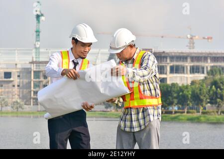 Two Engineer holding blueprint talking discussion building project real estate Stock Photo