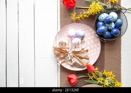 Plates with Easter cake, flowers and Easter eggs. Table setting for the Easter holiday copy space. Stock Photo