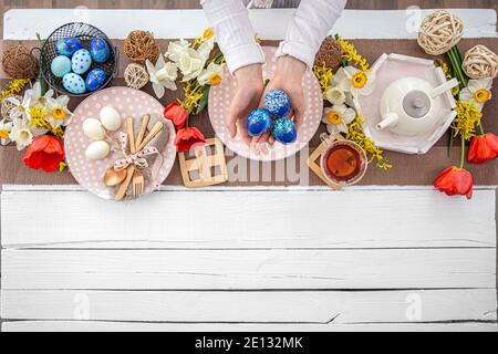 Festive Easter table with homemade Easter cake, tea, flowers and decor details copy space. Family celebration concept. Stock Photo