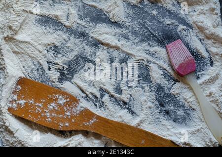 Cooking concept, minimalism. Kitchen items, wooden spatula, silicone brush, baking dish, flour on a black background. View from above. Copy space Stock Photo