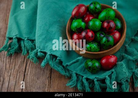 Easter colored eggs. Quail egg of green and red color on a wooden background. Willow branch. Happy Easter greeting card. Place for your text. Food on Stock Photo