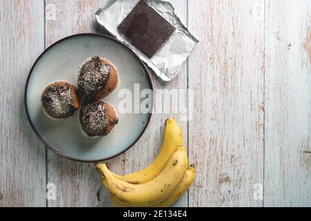 Top view flat lay on chocolate muffin cakes with banana on the table Stock Photo