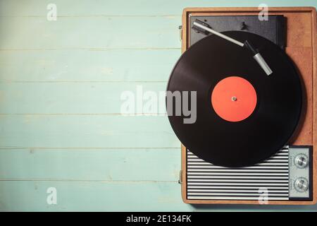 Vintage gramophone with a vinyl record on rustic wooden table, top view and copy space. Stock Photo