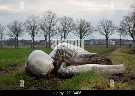Discarded mattresses, dumped along a country road, in the background a city skyline Stock Photo