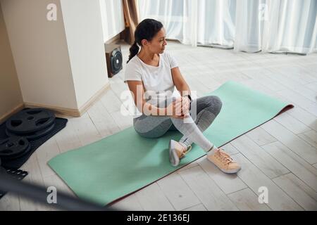 Pensive dark-haired sportswoman at her home gym Stock Photo