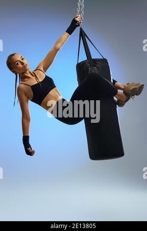 fit beautiful woman with boxing bandages and punching bag on studio background. full lenth Stock Photo