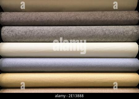 Rolled up rolls of vinyl wallpaper. Different textures and colors, as background. Beige, gray wallpapers for the wall. Decorative materials Stock Photo