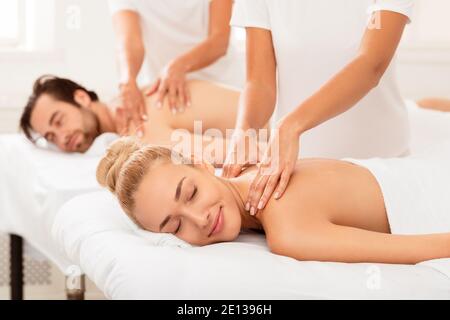 Relaxed Girlfriend And Boyfriend Enjoying Massage Lying On Beds Indoors Stock Photo