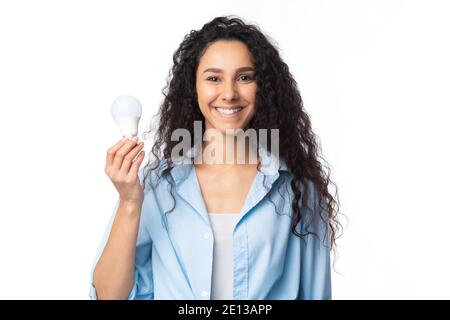 Happy Woman Showing Energy-Saving Light Bulb Posing On White Background Stock Photo