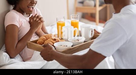 Cropped of african man bringing breakfast in bed for woman Stock Photo