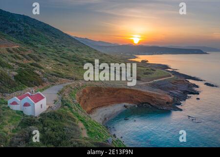 Gorgeus sunset over sea with waves, rocks and an old church in  Milatos, Crete, Greece. Stock Photo
