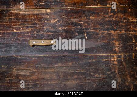 Old rusty kitchen knife on a rustic wooden cutting board placed to the center in an overhead view with copyspace Stock Photo