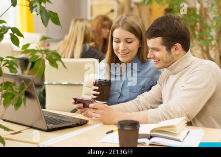 Young beautiful couple working on a laptop together copyspace coffee drinking coworkers colleagues students studying education technology internet onl Stock Photo