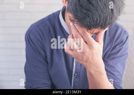 Young man suffering headache and covering his face with hand  Stock Photo