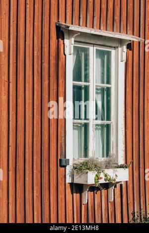 Window on the wall of the red wooden house in Finland Stock Photo